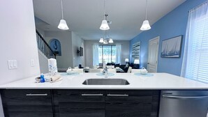 Een moderne keuken met een wit aanrecht, donkerhouten kastjes, een roestvrijstalen spoelbak en hanglampen.