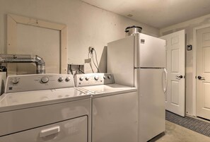 Un espace buanderie comprenant un lave-linge, un sèche-linge, un chauffe-eau et un réfrigérateur.