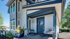 Ett modernt hus med en inglasad veranda, en ytterdörr samt ett litet bord och en stol.