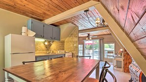 A kitchen with a wooden table, cabinets, and a refrigerator.