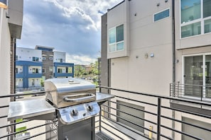 A balcony with a stainless steel grill, a metal railing, and a view of modern apartment buildings. - Trendy Denver Townhome - Walk to Mile High Stadium (Denver)