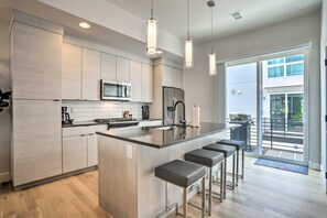 A modern kitchen with a central island, bar stools, a microwave, and a refrigerator. - Trendy Denver Townhome - Walk to Mile High Stadium (Denver)