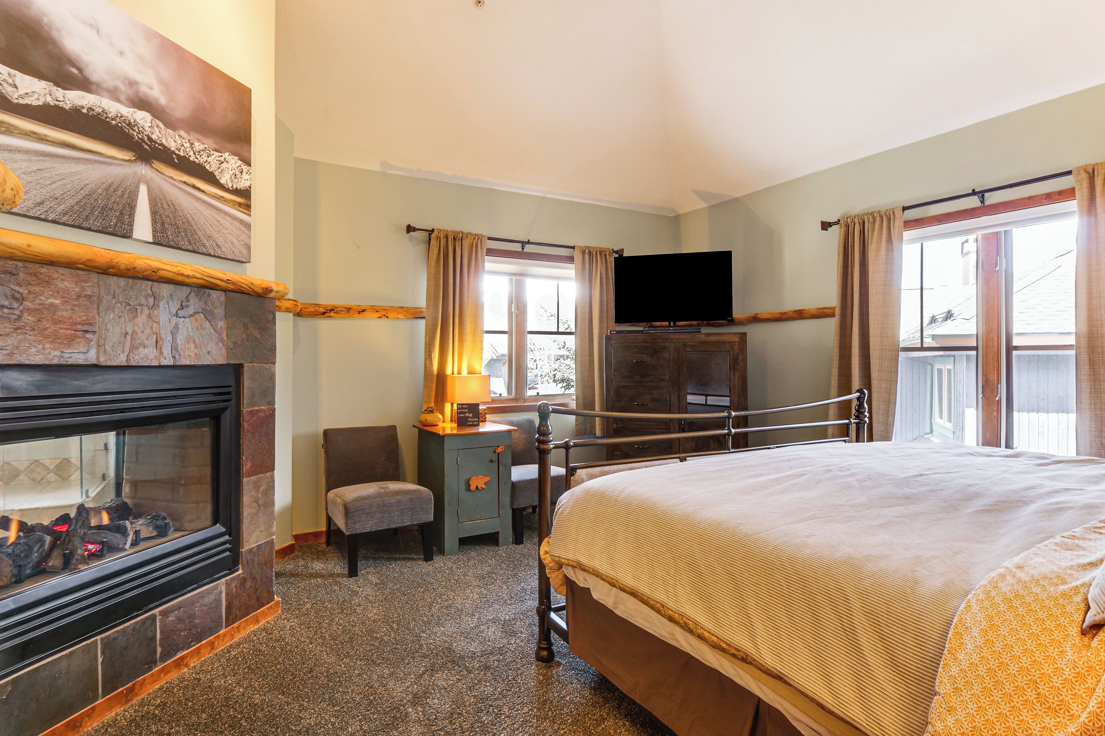 A hotel room with a fireplace, a bed, a television, and a window with curtains.