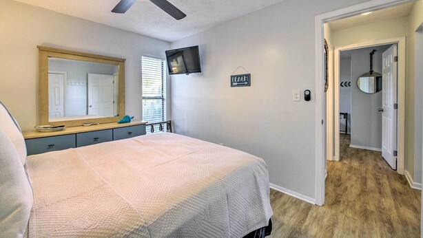 Un dormitorio con cama, ventilador de techo, televisor, espejo y un cartel que dice 'BEACH'.