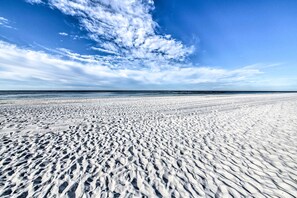 A wide sandy beach with footprints, a clear sky, and the ocean in the background. - PCB Condo Rental w/ Pool Access, Steps to Beach! (Panama City Beach)
