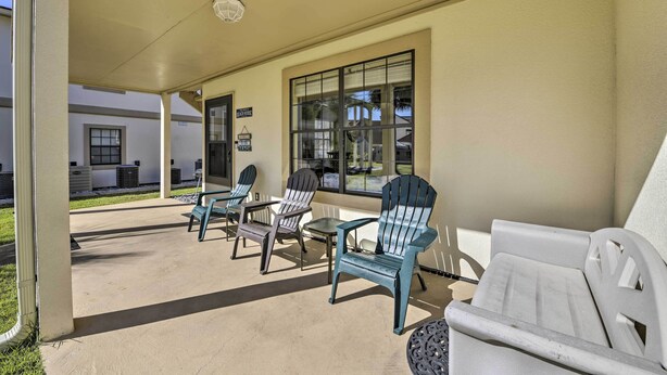A covered outdoor seating area with Adirondack chairs and a white sofa, a glass door entrance, and a sign that reads "Welcome to Beach." - 1st-floor Resort Condo in PCB - Walk to Beach! (Panama City Beach)