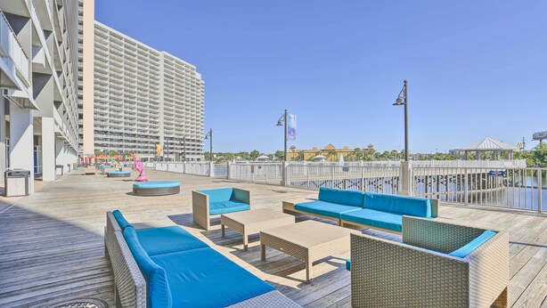 A rooftop deck with wicker furniture and a view of a tall building. - 18th-floor PCB Resort Condo w/ Amazing Gulf View! (Panama City Beach)