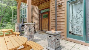 Une cabane en bois avec une cheminée en pierre, un foyer et une table de pique-nique.