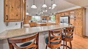 A spacious kitchen with wooden cabinets, a granite countertop, and multiple hanging pendant lights. - The Vineyard Country Farm Home at Grand Valley (Grand Junction)