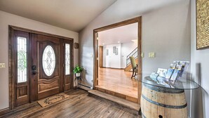 A wooden front door with glass panels, a glass-top table with brochures, and a wooden barrel as a side table. - The Vineyard Country Farm Home at Grand Valley (Grand Junction)