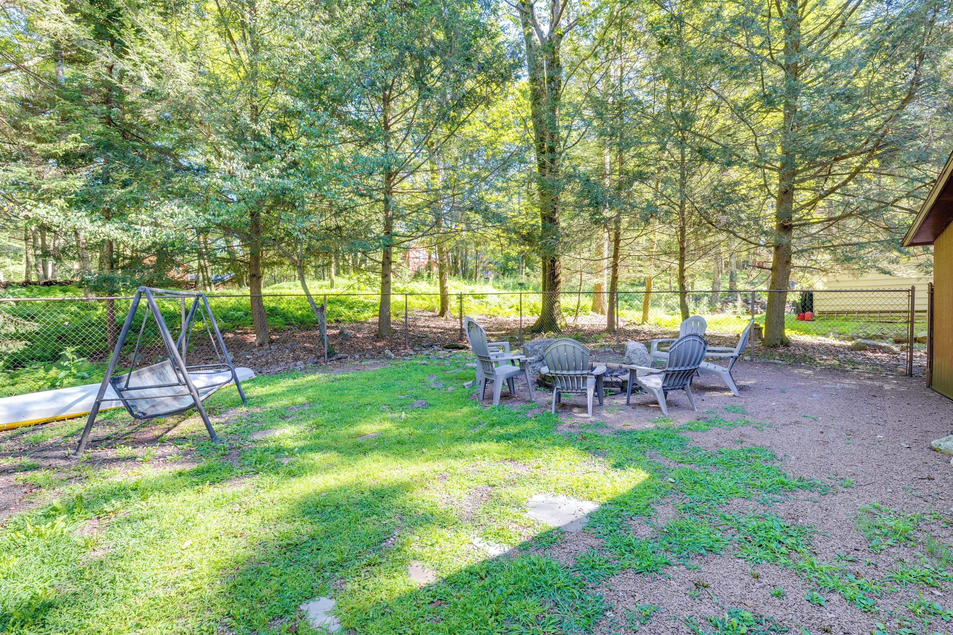 A patio area with a swing set, a table with chairs, and a fenced garden.