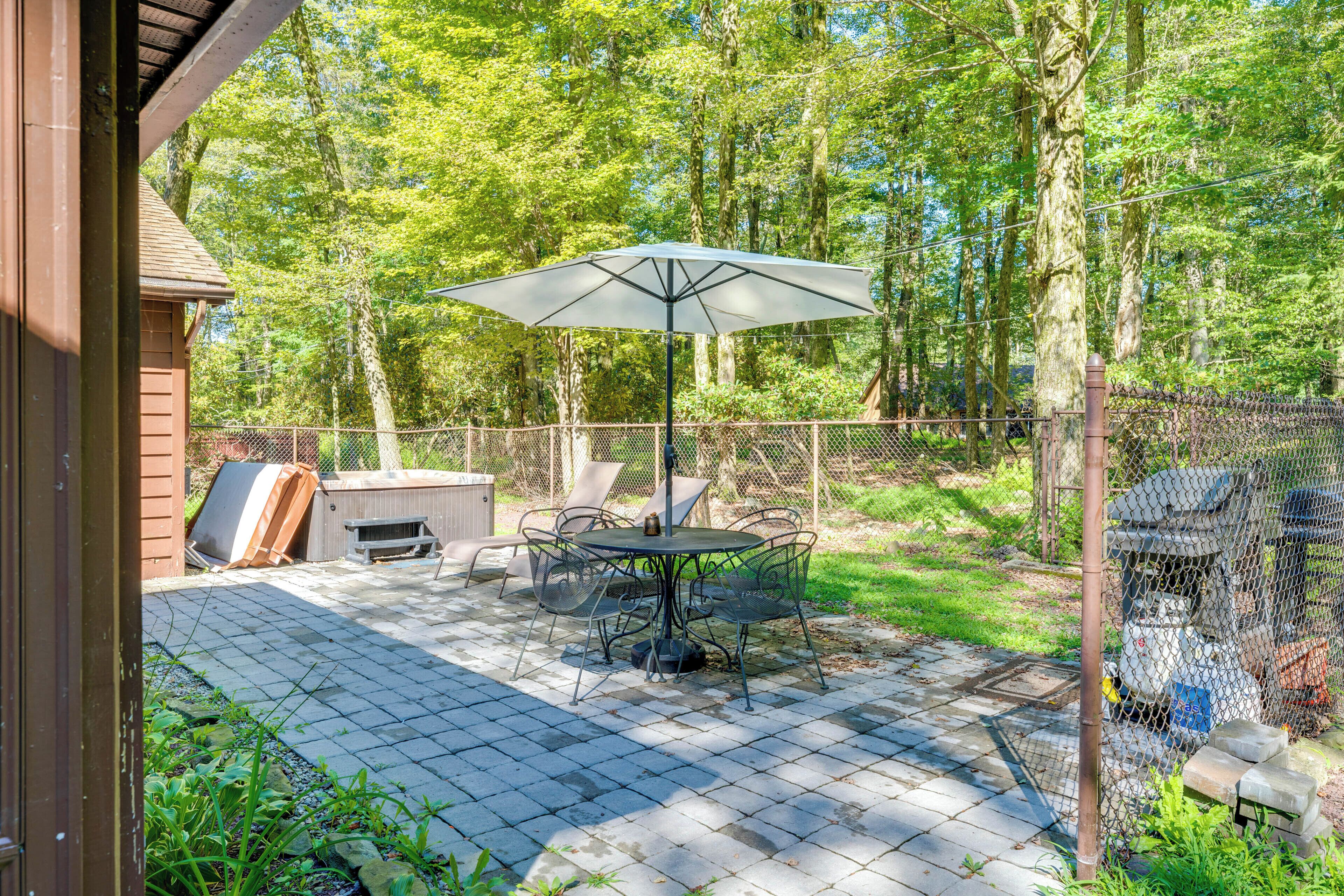 Eine Terrasse mit Tisch und Stühlen, umgeben von einem Holzzaun und Bäumen.