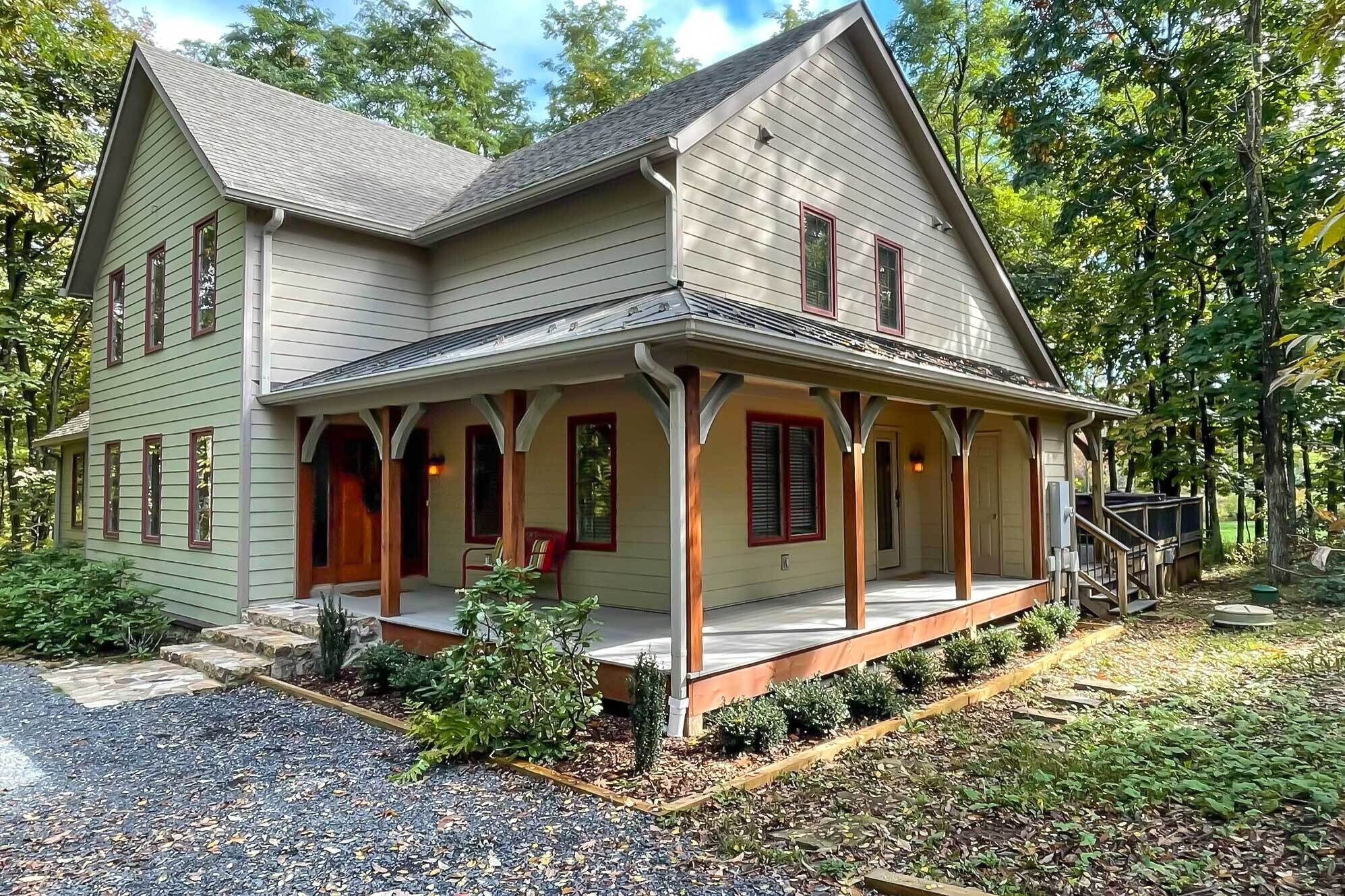 A two-story house with a porch, a front door, and a staircase leading to the entrance.