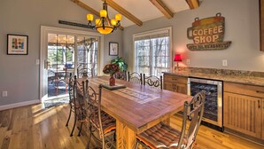 A spacious dining area with a wooden table and chairs, a chandelier, and a coffee shop sign on the wall. - Spacious Wintergreen Resort Home w/ Hot Tub! (Nellysford)