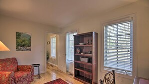 A living room with a red patterned sofa, a dark wooden bookshelf, and a red rug. - Spacious Wintergreen Resort Home w/ Hot Tub! (Nellysford)