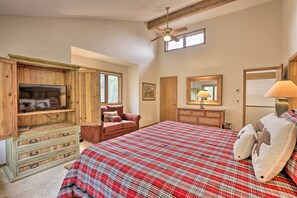 A bedroom with a large bed, wooden furniture, a ceiling fan, and a television.