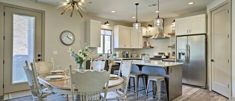 A modern kitchen with a central island, pendant lighting, and a built-in refrigerator.