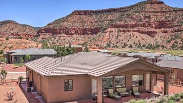 A modern house with a patio area, surrounded by a desert landscape and red rock formations.