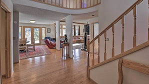 A spacious living area with hardwood floors, a red chair, a sofa, and a staircase with wooden railings. - ~ 1 Mi to Downtown: Buena Vista Riverfront Escape! (Buena Vista)