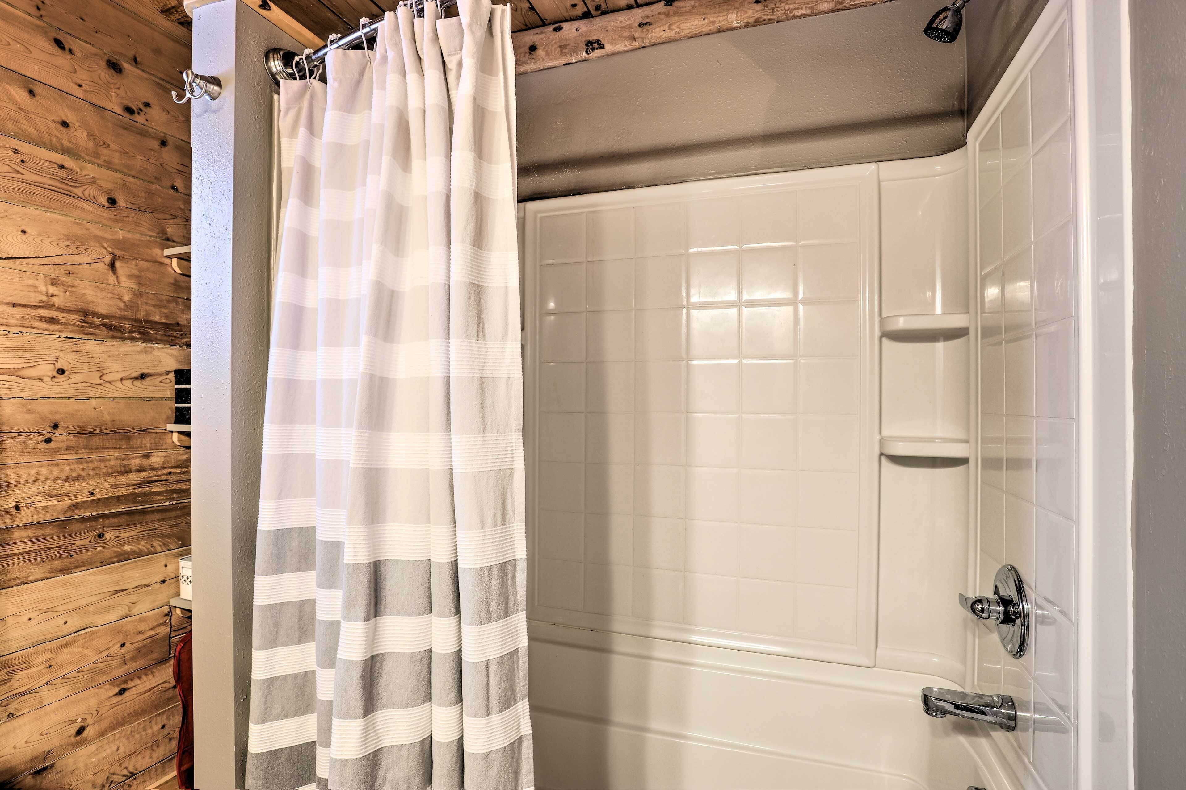Een badkamer met een douche, betegelde wanden en een houten accentmuur.