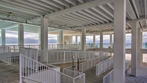 A covered outdoor area with white railings and a wooden deck, featuring a view of the beach. - Panama City Beach Studio w/ Pool & Beach Access (Panama City Beach)