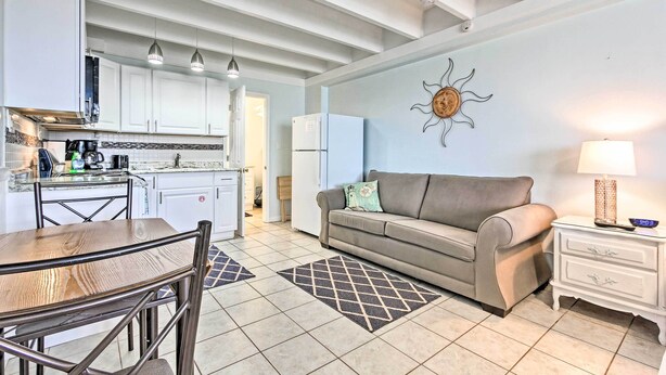 A modern kitchen with white cabinets, a dining table, and a sofa in a living area. - Panama City Beach Studio w/ Pool & Beach Access (Panama City Beach)