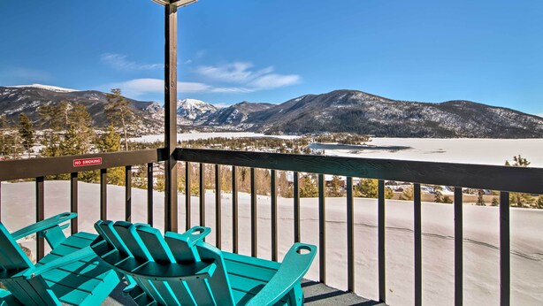 Un balcon avec des chaises turquoise et une vue sur des montagnes enneigées.