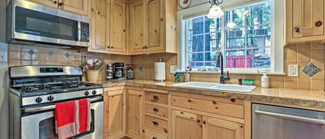 A kitchen with wooden cabinets, a stainless steel stove, a microwave, and a sink.