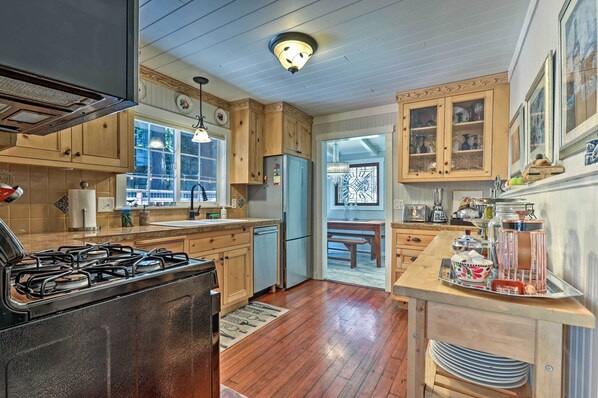 A kitchen with wooden cabinets, a gas stove, a refrigerator, and a dining area with a table and chairs.