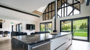 A modern kitchen with a large island, large windows, and a view of the outdoors. - The Northern Escape HOT TUB & SAUNA! (blue mountain)