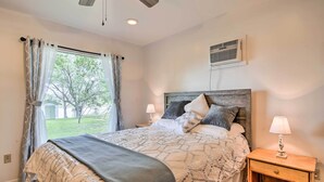 A bedroom with a bed, nightstands, a lamp, and a window with curtains. - Riverfront Family Home: Yard, Orchard, Dock! (Los Fresnos)