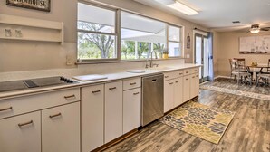 A kitchen with white cabinets, a stainless steel dishwasher, and a window overlooking a garden. - Riverfront Family Home: Yard, Orchard, Dock! (Los Fresnos)