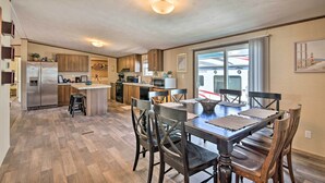Une cuisine spacieuse dotée de meubles en bois, d’un îlot central et d’un coin repas avec des chaises et une table en bois foncé.
