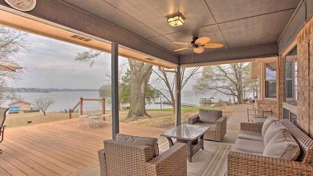 A covered outdoor deck with wicker furniture, a ceiling fan, and a view of a lake. - Roomy Texas Lake Retreat w/ Private Boat Ramp (Frankston)