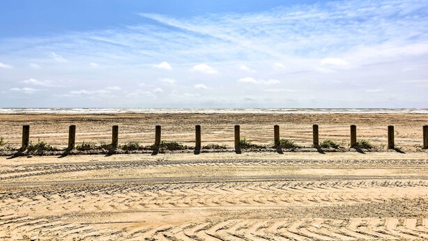 A sandy beach with wooden posts and tire tracks. - Near Port Aransas Beach: Condo w/ Pool Access (Port Aransas)