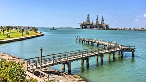 A pier extending into calm waters with an offshore oil platform in the background. - Near Port Aransas Beach: Condo w/ Pool Access (Port Aransas)