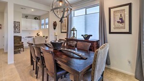 A dining area with a dark wooden table, leather chairs, and a hanging light fixture. - Resort Pool & Hot Tub: 55+ Indio Desert Oasis (Indio)