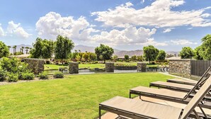 A well-maintained outdoor area with a lawn, stone structures, and a pool. - Resort Pool & Hot Tub: 55+ Indio Desert Oasis (Indio)