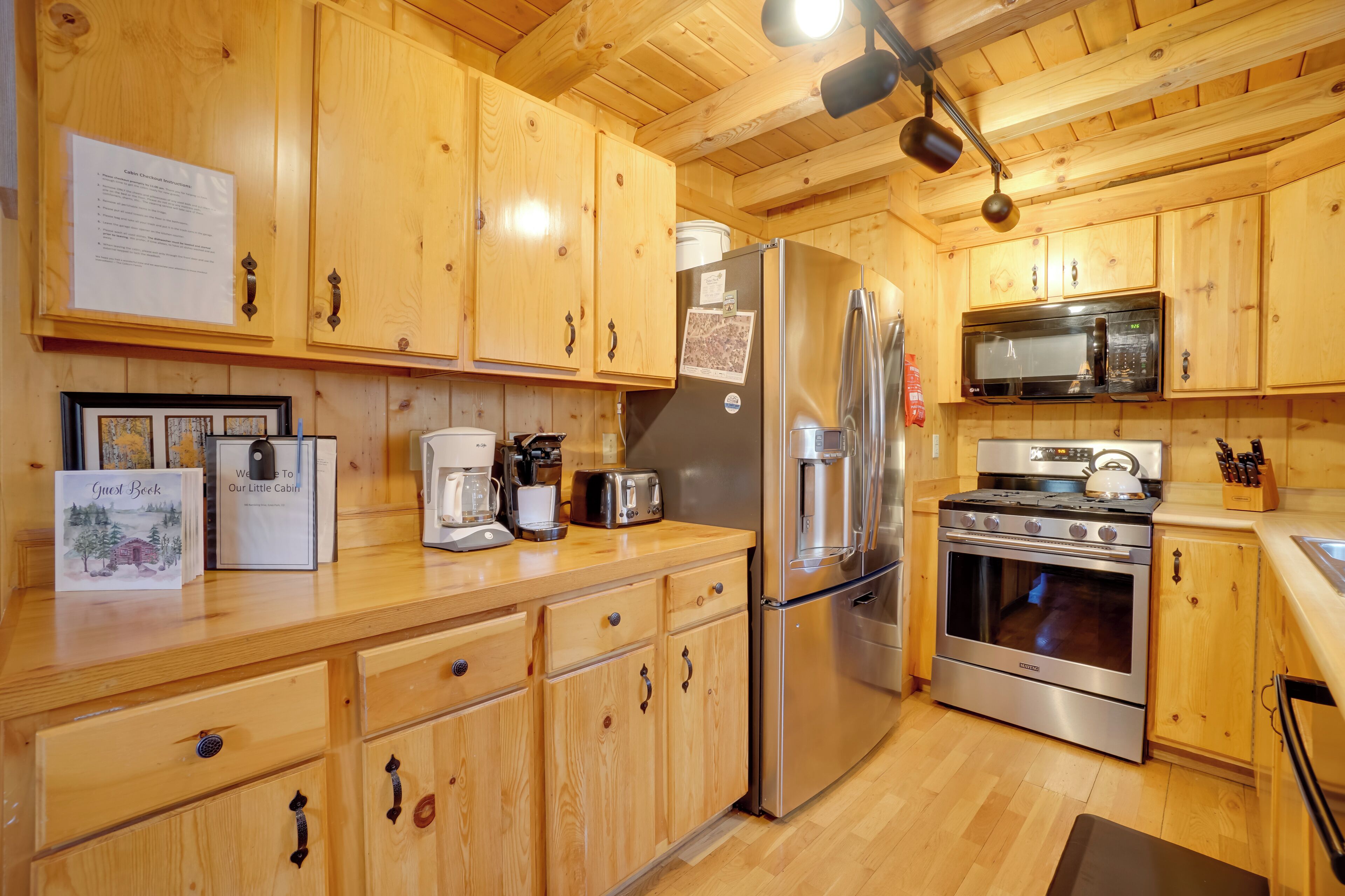 Une cuisine de style rustique, avec des éléments en bois, comprenant un réfrigérateur, une cuisinière, un four à micro-ondes et des placards en bois.