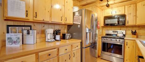 Une cuisine de style rustique, avec des éléments en bois, comprenant un réfrigérateur, une cuisinière, un four à micro-ondes et des placards en bois.