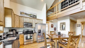 A spacious kitchen with wooden cabinets, stainless steel appliances, and a dining area with wooden chairs and a table.