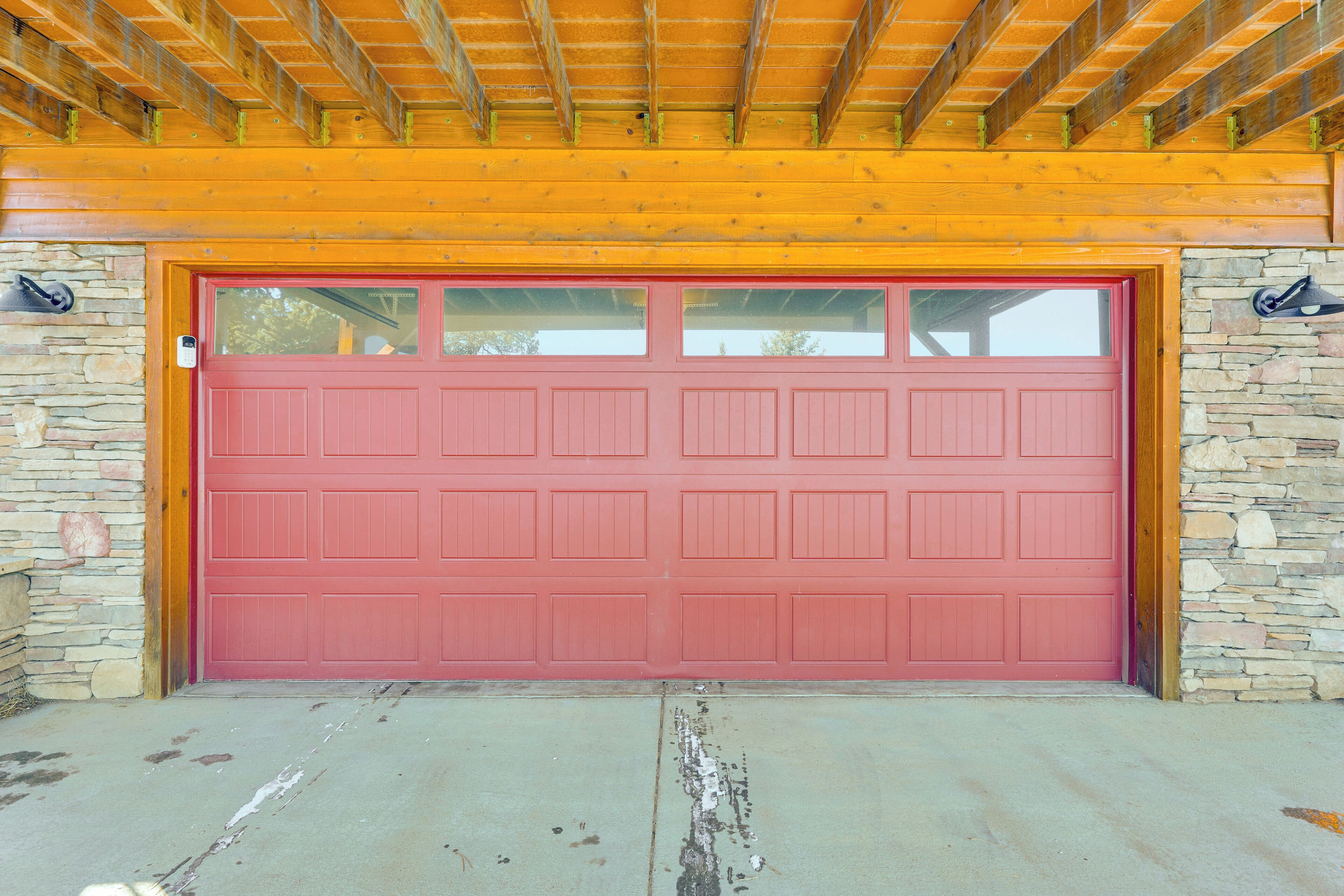 Une porte de garage rouge, avec des murs en pierre et un plafond en bois.