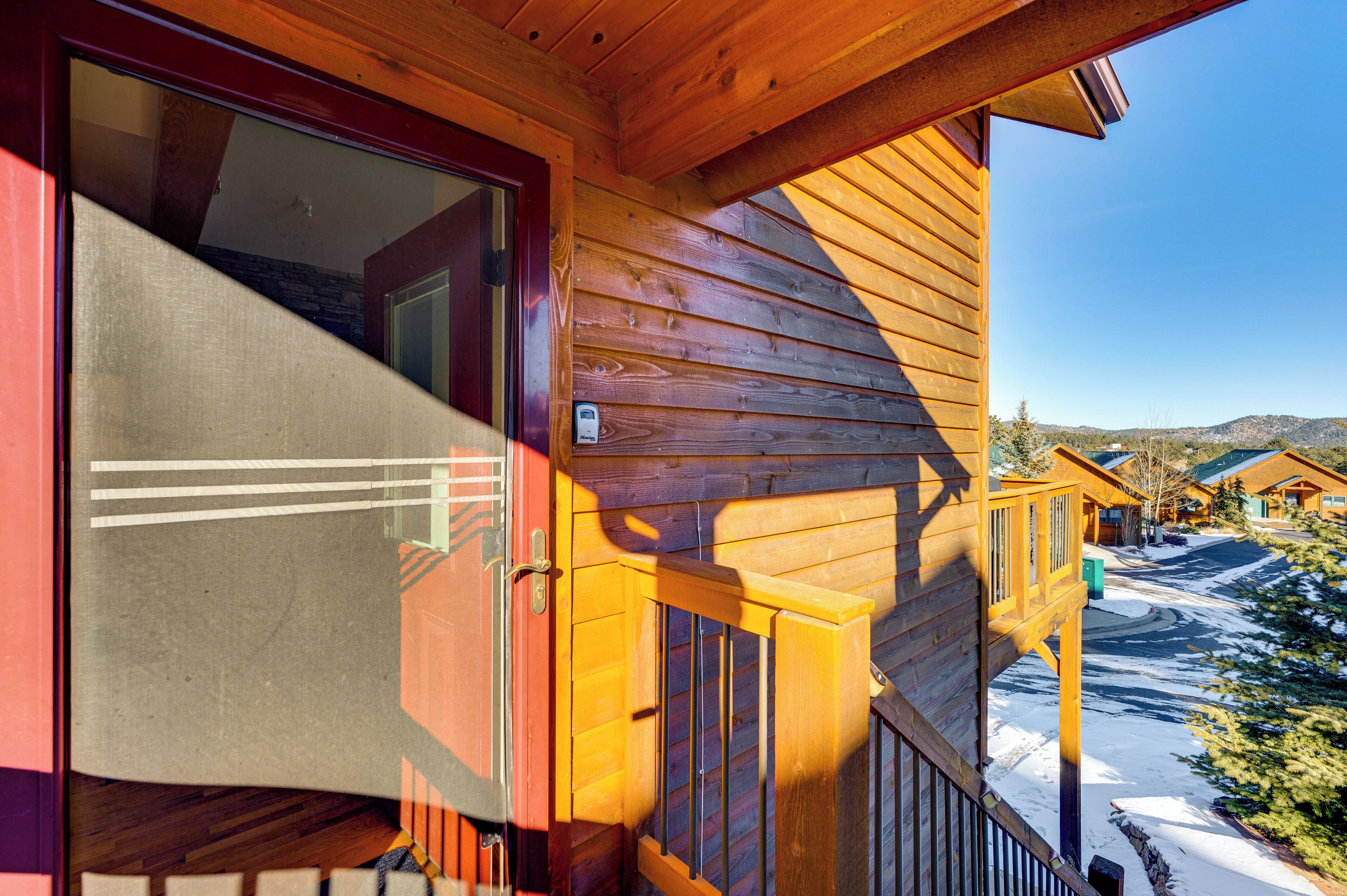 Une cabane en bois dotée d’un balcon, d’une porte et offrant une vue sur un paysage enneigé.