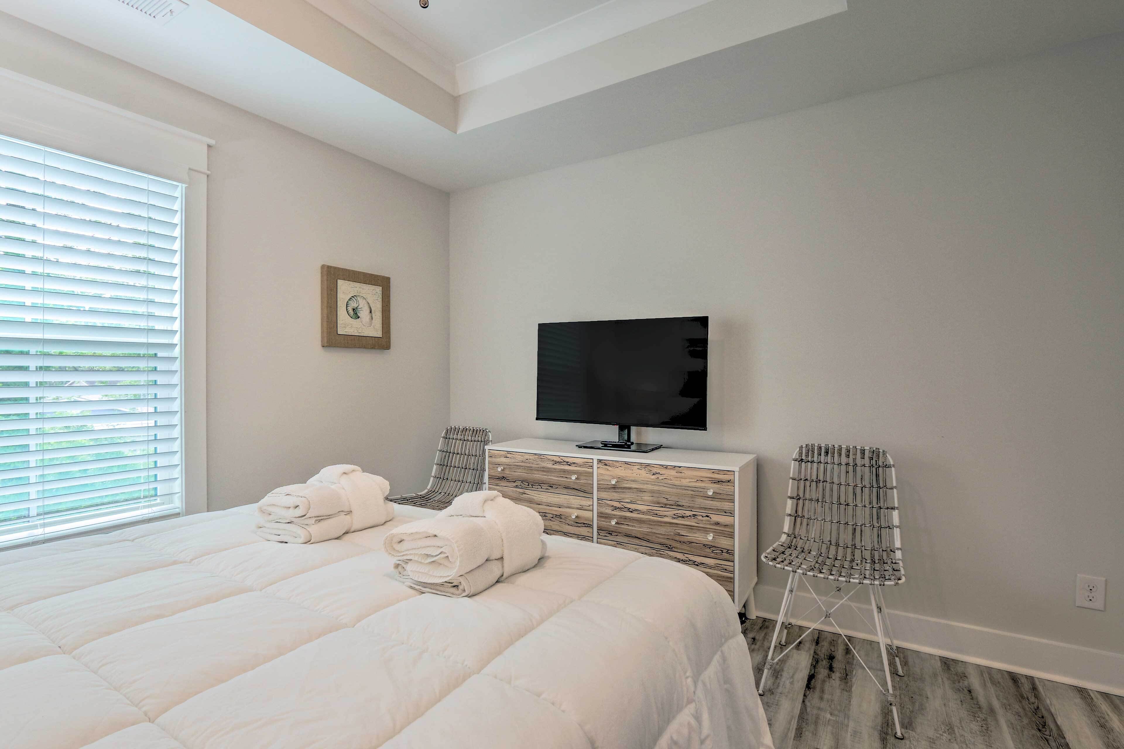 Une chambre à coucher avec un grand lit, une télévision, une commode et deux chaises.