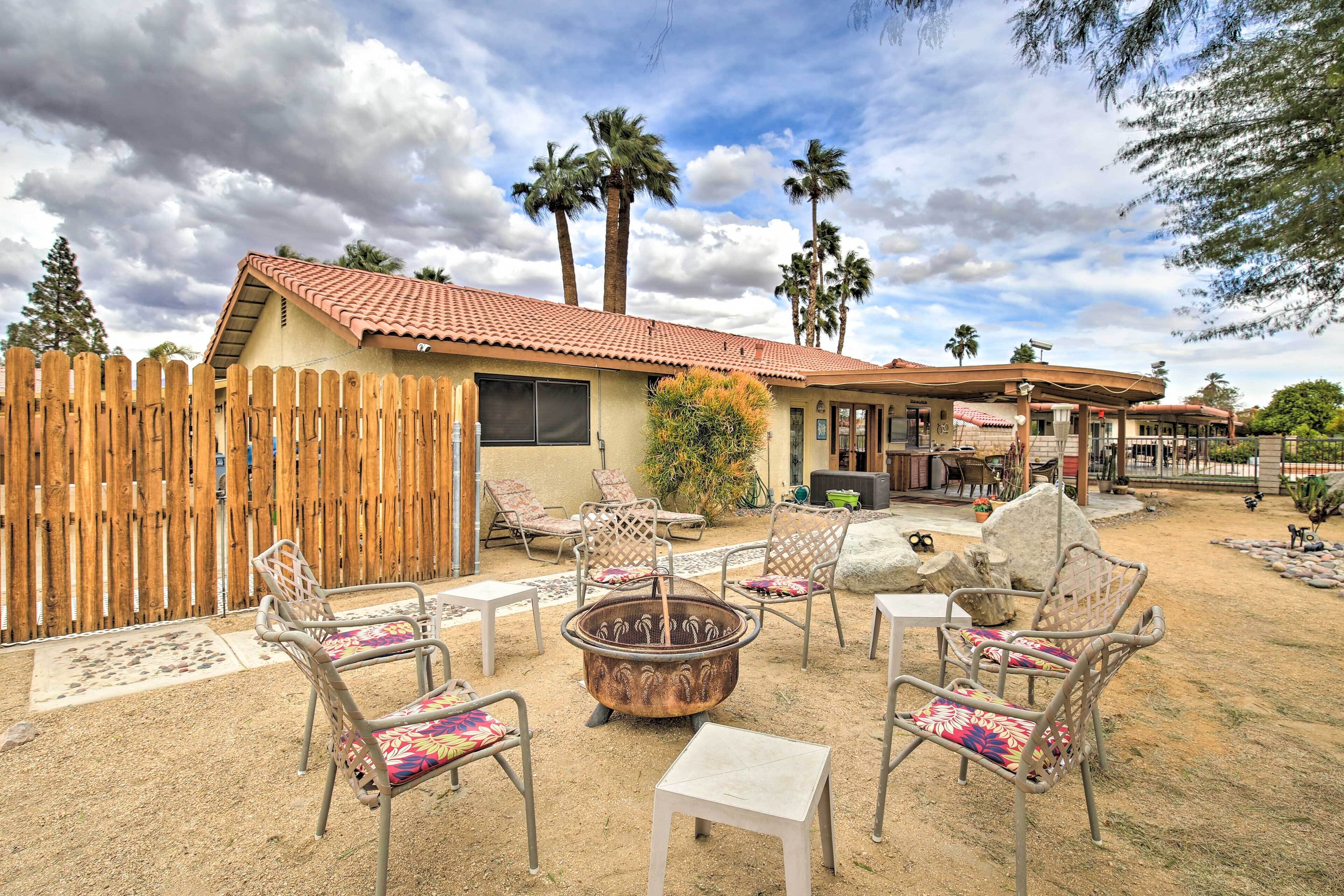 A patio area with outdoor furniture, a fire pit, and a wooden fence.
