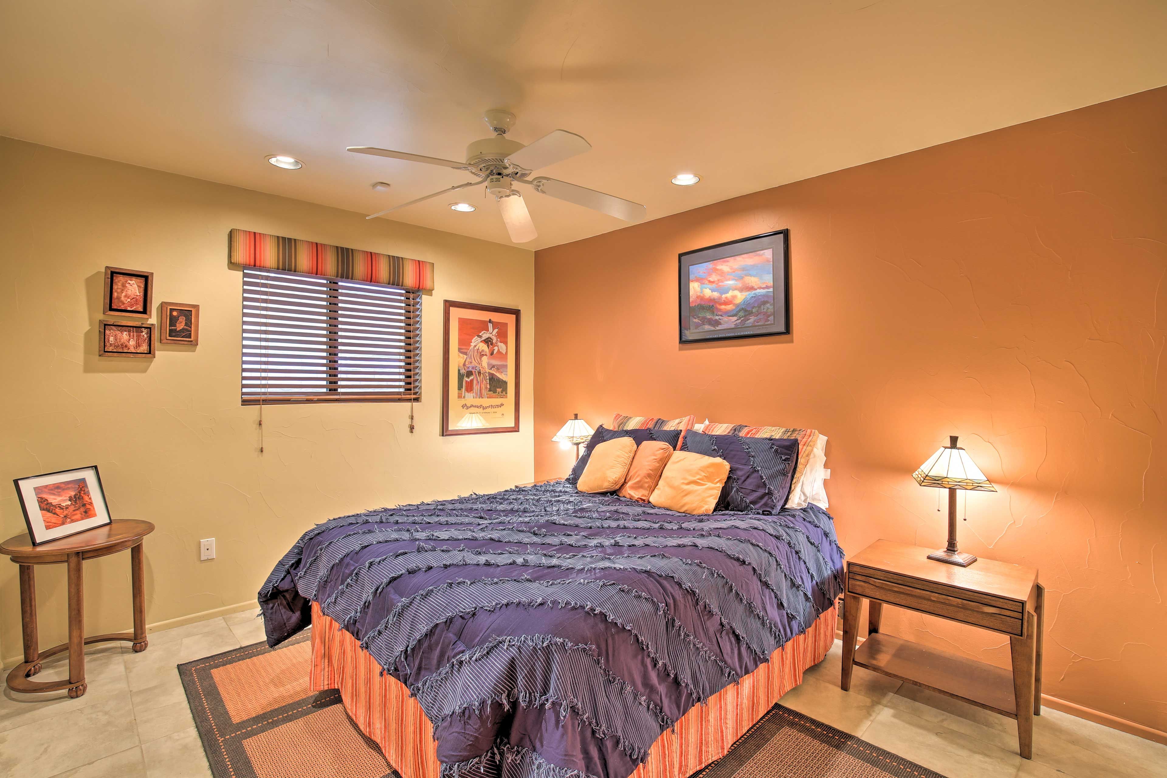 A bedroom with a bed, a nightstand, a ceiling fan, and a window with blinds.