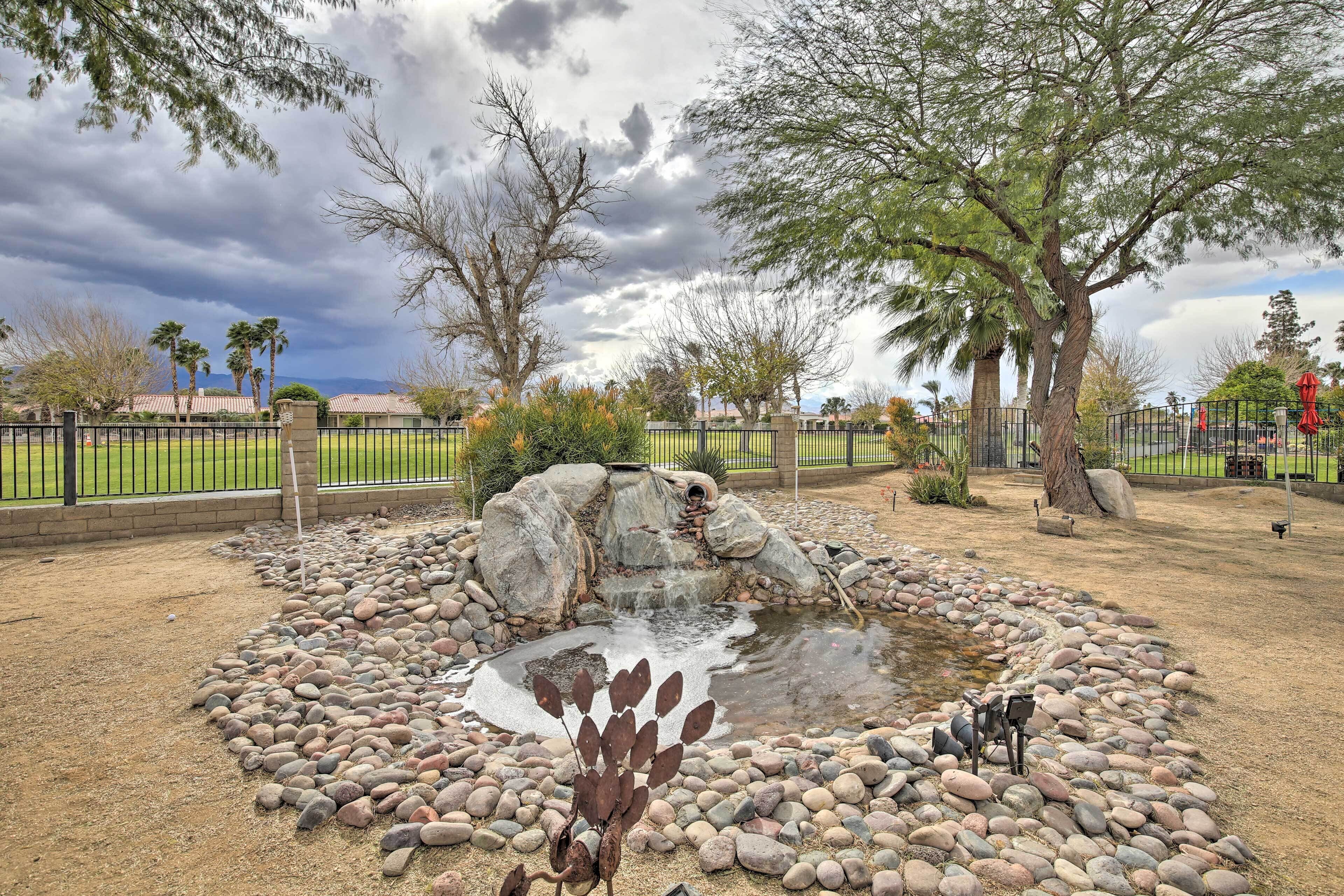 Un jardín ajardinado con un estanque, rocas y árboles.