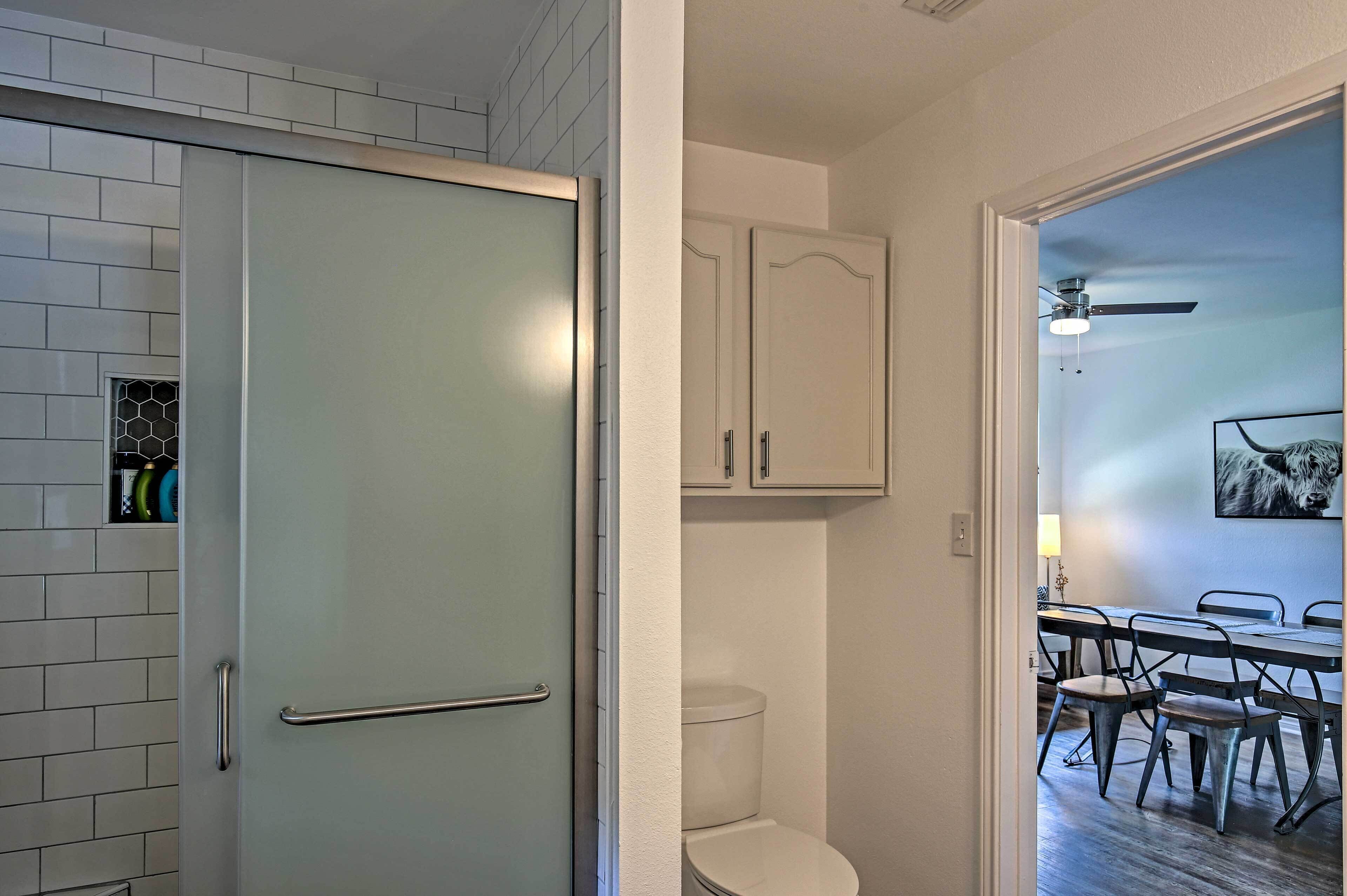 A bathroom with a toilet, cabinets, and a shower area.