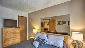A hotel room with a bed, a wooden dresser, a TV, a lamp, and a mirror. - Walk to Main St: Ski-in/ski-out Breckenridge Condo (Breckenridge)