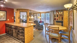 A modern kitchen with wooden cabinets, a central island, and a dining area with wooden chairs and a table. - Walk to Main St: Ski-in/ski-out Breckenridge Condo (Breckenridge)